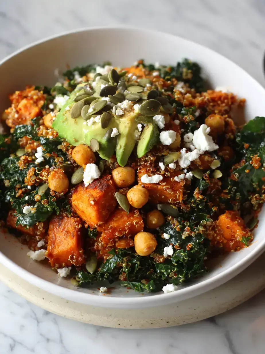 A beautifully arranged vegetable grain bowl with quinoa, roasted sweet potatoes, chickpeas, kale, and avocado
